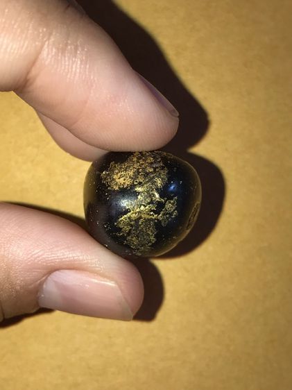 เหล็กไหล รูปหยดน้ำ ขนาดประมาณ 1 นิ้ว ใหญ่เท่ากับเม็ดขนุน เป็นเหล็กไหลปิดทอง มีลักษณะเป็นก้อนสีดำนิลอมเขียวปีกแมลงทับปนดำ เป็นมันด้านๆ ไม่แวว รูปที่ 5