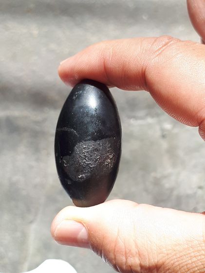 เหล็กไหล ทรงยาวรี สีดำสลับสีน้ำตาล มีลายเป็นธรรมชาติ ขนาดประมาณ 2 นิ้ว มีน้ำหนักมาก จะมีลักษณะเนื้อระเอียด มีรูตรงด้านหัวสำหรับเป็นทางเข้า อ รูปที่ 10