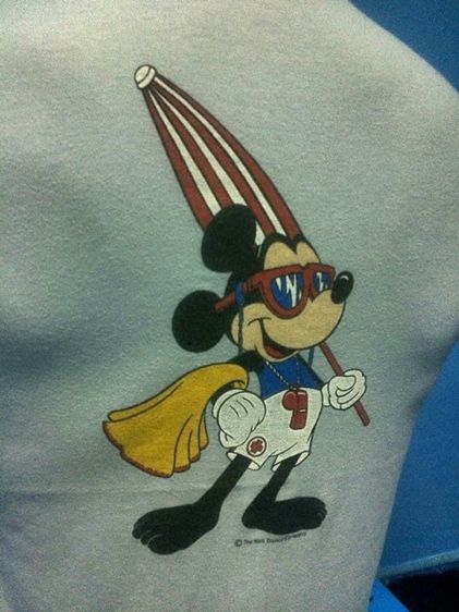 เสื้อยืดมิกกี้เมาส์ ด้านหน้าสกรีนหน้ามิกกี้อยู่ในห่วงยาง LIFE GUARD FLORIDA ด้านหลังสกรีนมิกกี้ยืนถือร่ม The Walt Disney Company ผ้า 50 50 รูปที่ 4
