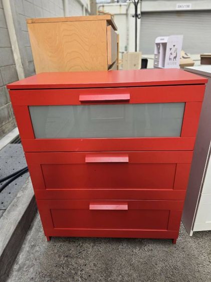 ไม้ ตู้ลิ้นชัก IKEA รุ่น BRIMNES สีแดงที่มีลิ้นชัก 3 ช่องจุดเด่นคือช่องลิ้นชักบนสุดเป็นกระจกฝ้าตู้นี้มีความสูงประมาณ 95เซน