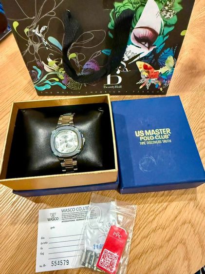 นาฬิกาข้อมือในรูปภาพคือแบรนด์ US Master Polo Club รุ่นทรงเหลี่ยมมน (คล้ายทรง Nautilus) หน้าปัดสีเงิน/ขาว